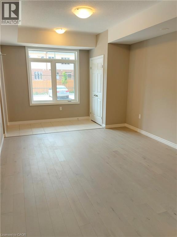 Spacious room featuring light wood-finish flooring, neutral wall tones, and recessed lighting - 26 Wheat Lane, Kitchener, ON - Indoor Photo Showing Other Room