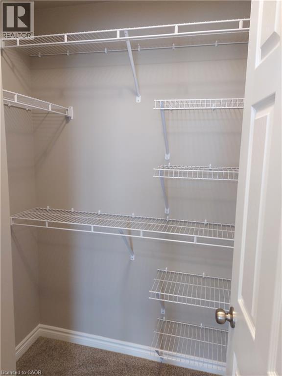 Walk-in closet featuring built-in wire shelving, white trim, and neutral-toned wall paint - 26 Wheat Lane, Kitchener, ON - Indoor With Storage