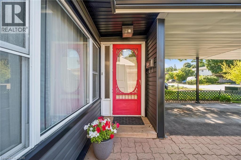 Black horizontal siding exterior with a bright red entry door and a covered carport - 460 Parkview Crescent, Cambridge, ON - Outdoor With Exterior