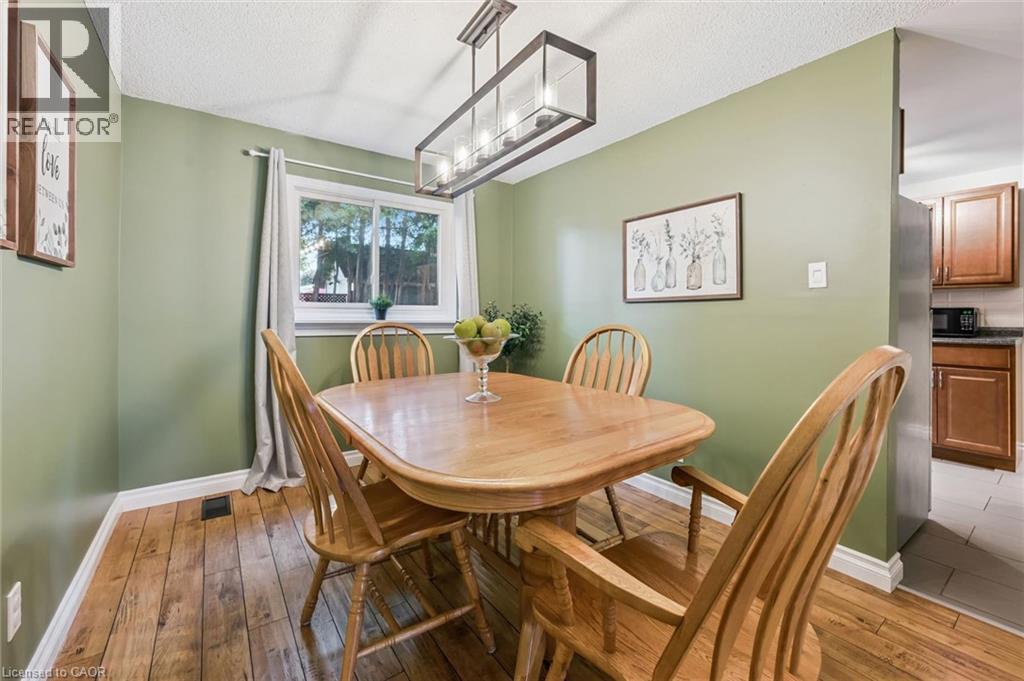Wood-finish flooring with a rectangular window, white trim, and a linear pendant light fixture - 460 Parkview Crescent, Cambridge, ON - Indoor Photo Showing Dining Room