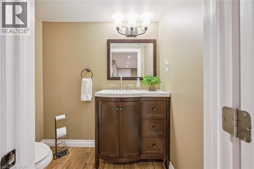 Wood-finish flooring with a rounded vanity featuring a white countertop and rectangular undermount sink - 460 Parkview Crescent, Cambridge, ON - Indoor Photo Showing Bathroom