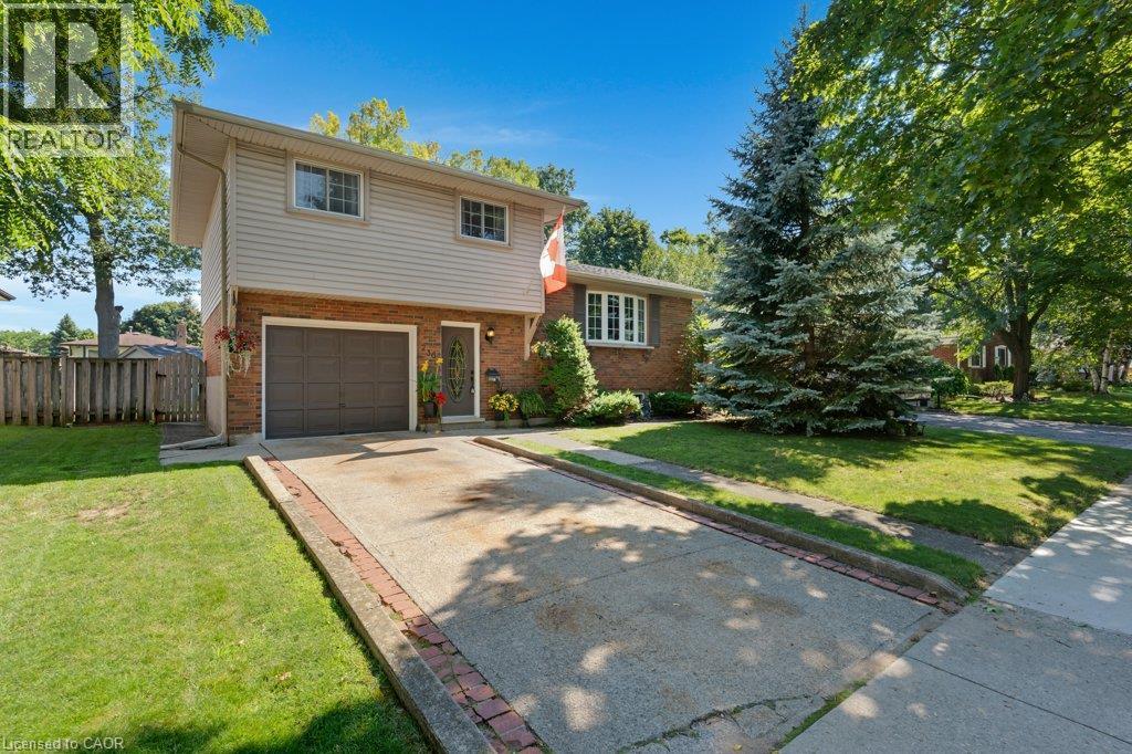 Brick and siding exterior with an attached garage, paved driveway, mature trees, and a manicured lawn - 236 Winston Boulevard, Cambridge, ON - Outdoor