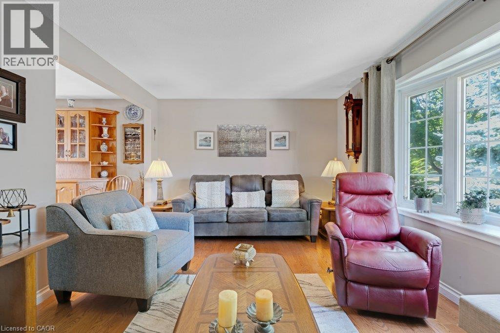 Bright, light-filled living room showcasing hardwood flooring, large multi-pane windows with natural sidelighting, neutral wall finishes, and built-in cabinetry with glass-front doors - 236 Winston Boulevard, Cambridge, ON - Indoor Photo Showing Living Room