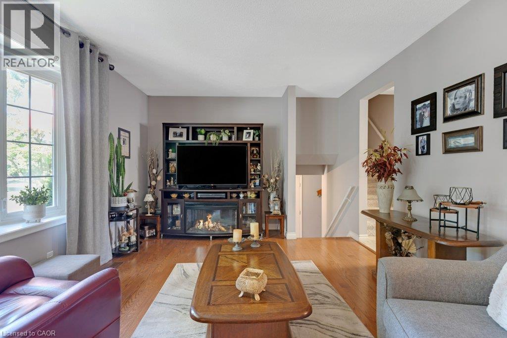 Hardwood flooring throughout, built-in media console with fireplace, large window with ample natural light, neutral wall colors, and multi-level architectural features - 236 Winston Boulevard, Cambridge, ON - Indoor Photo Showing Living Room