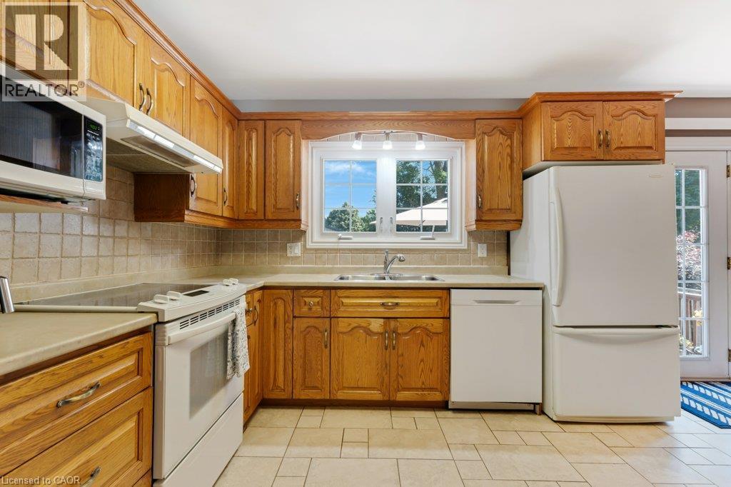 Wood-finish cabinetry, tile flooring, and a tile backsplash - 236 Winston Boulevard, Cambridge, ON - Indoor Photo Showing Kitchen With Double Sink