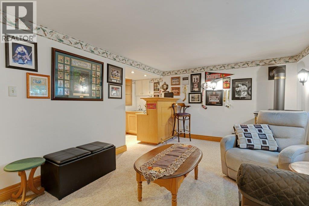 Open-concept living area featuring wood-finish flooring, decorative wall display with framed artwork, built-in cabinetry with display shelving, and a wood-frame upholstered sofa - 236 Winston Boulevard, Cambridge, ON - Indoor