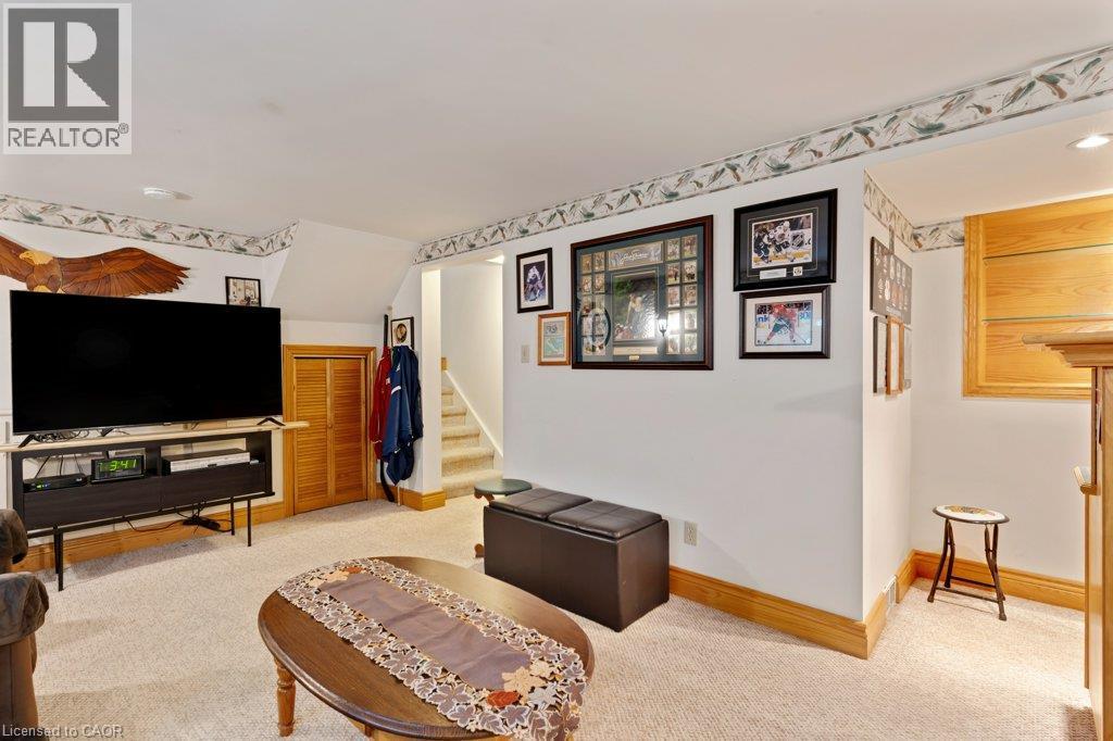 Finished basement recreation room featuring exposed beam ceiling detail, wood-trim framing, neutral carpeting, and built-in entertainment cabinetry - 236 Winston Boulevard, Cambridge, ON - Indoor