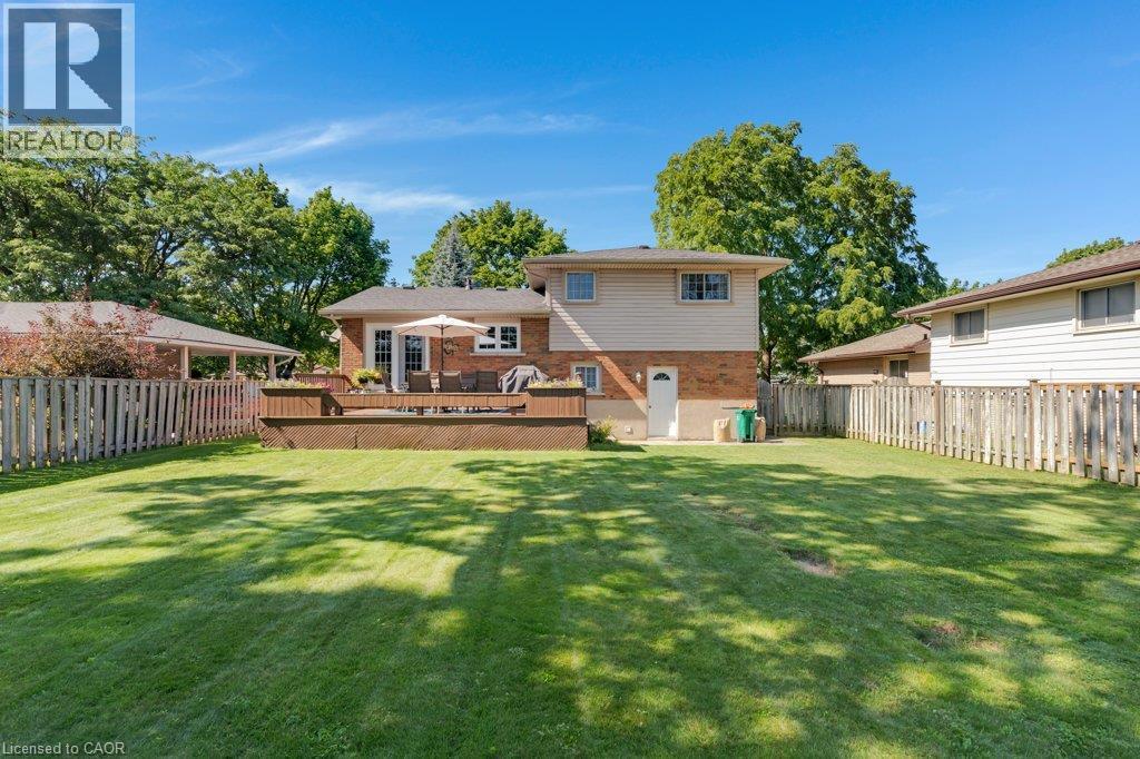 Expansive backyard featuring a manicured lawn, multi-level wood-finish deck, and wood picket fencing - 236 Winston Boulevard, Cambridge, ON - Outdoor With Deck Patio Veranda