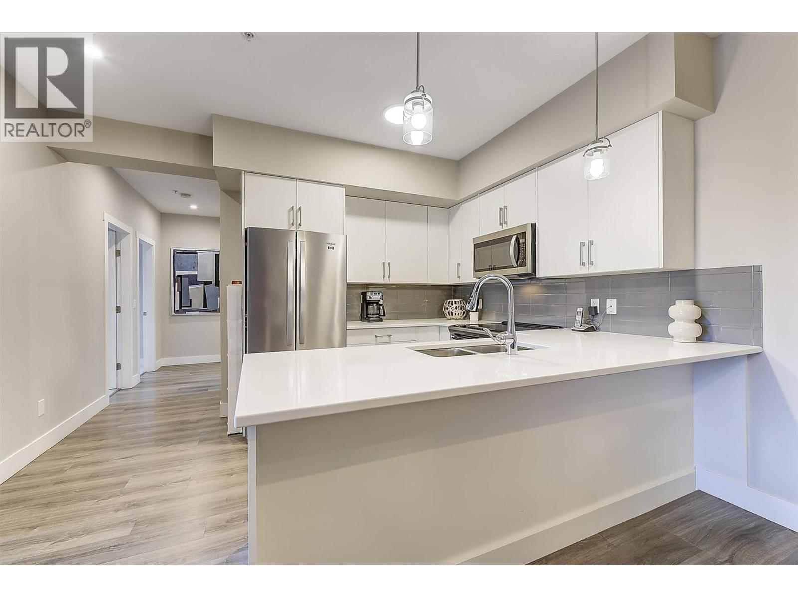 Quartz countertops, bright white cabinetry, contemporary lines, and stainless steel kitchen appliance package. - 3090 Burtch Road Unit# 201, Kelowna, BC - Outdoor