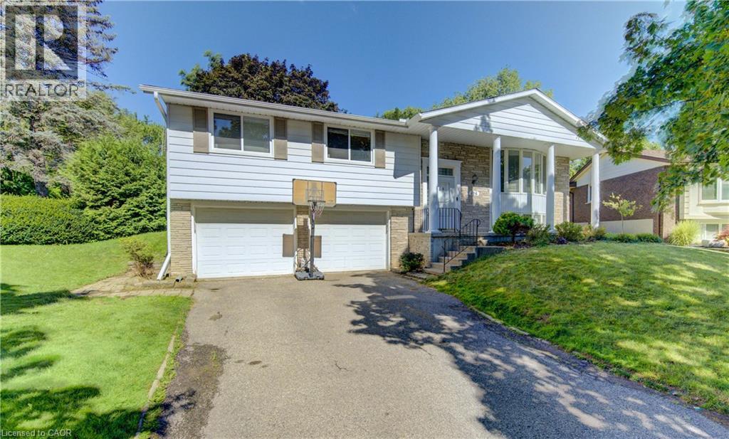 Split-level residence featuring a two-car garage with white doors, a stone facade, and a covered front entry with white columns - 106 Autumn Hill Crescent, Kitchener, ON - Outdoor With Facade
