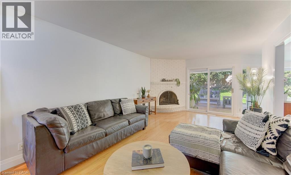 Bright interior space featuring light wood-finish flooring, a corner fireplace with painted brick surround, and white walls - 106 Autumn Hill Crescent, Kitchener, ON - Indoor Photo Showing Living Room