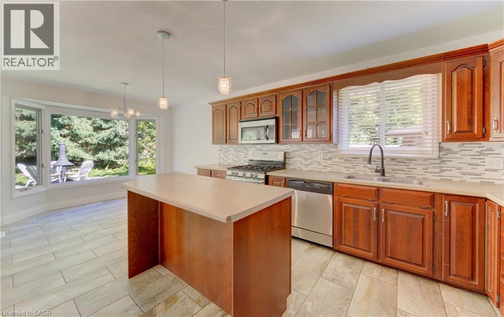Kitchen featuring wood cabinetry, stainless steel appliances, a center island with countertop, and tile flooring - 106 Autumn Hill Crescent, Kitchener, ON - Indoor Photo Showing Kitchen With Double Sink
