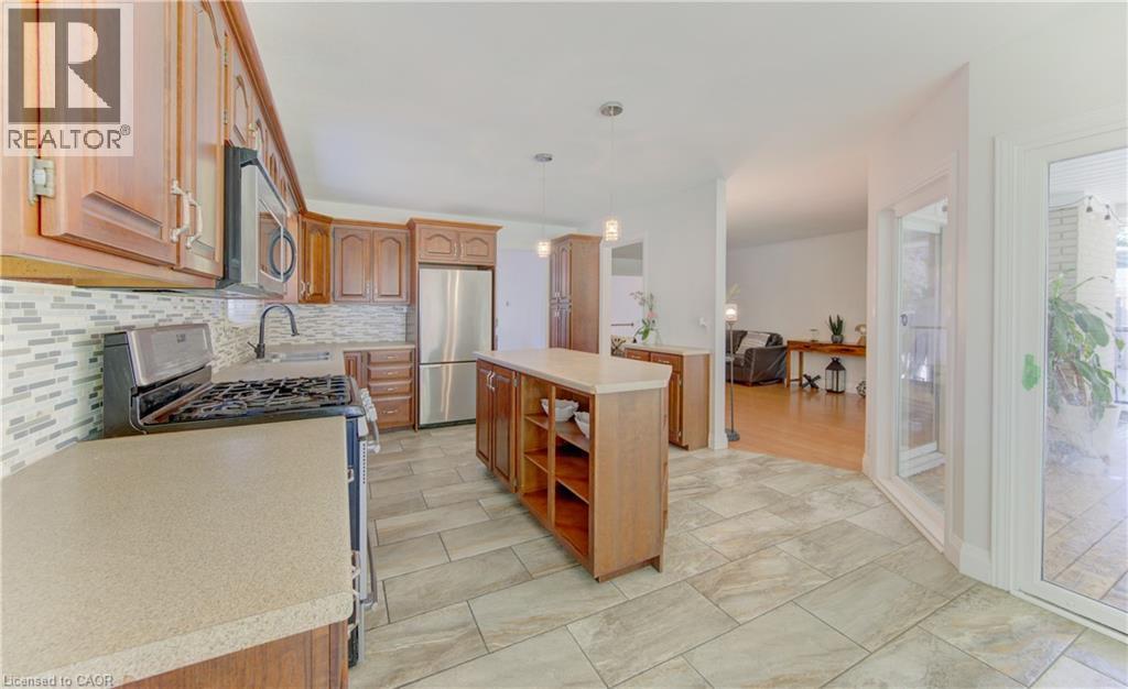 Kitchen with wood-finish cabinetry, stainless steel appliances, and a mosaic tile backsplash - 106 Autumn Hill Crescent, Kitchener, ON - Indoor Photo Showing Kitchen