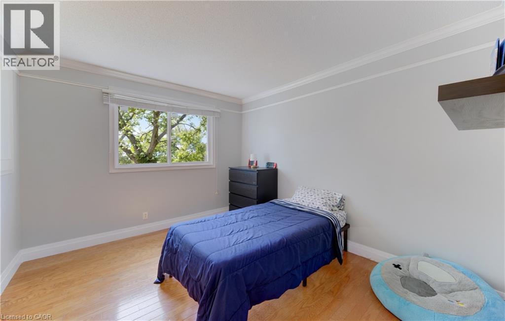 Light-filled room featuring wood-finish flooring, white crown molding, a large window with natural light, and a built-in floating shelf - 106 Autumn Hill Crescent, Kitchener, ON - Indoor Photo Showing Bedroom