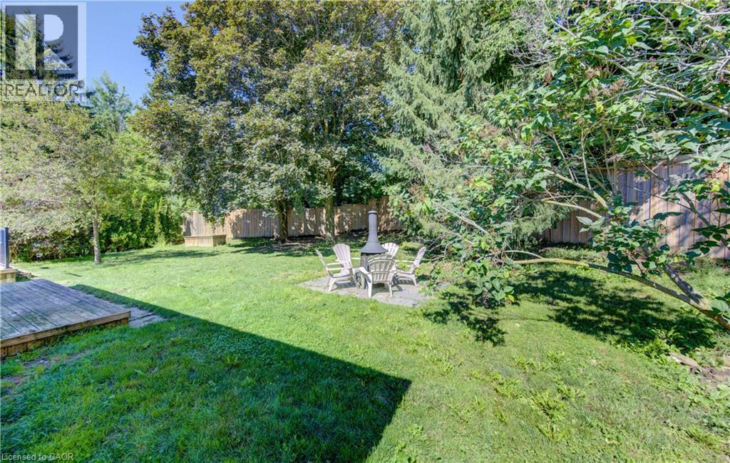 Expansive rear yard featuring a wood deck, a stone patio, mature trees, and a privacy fence - 106 Autumn Hill Crescent, Kitchener, ON - Outdoor