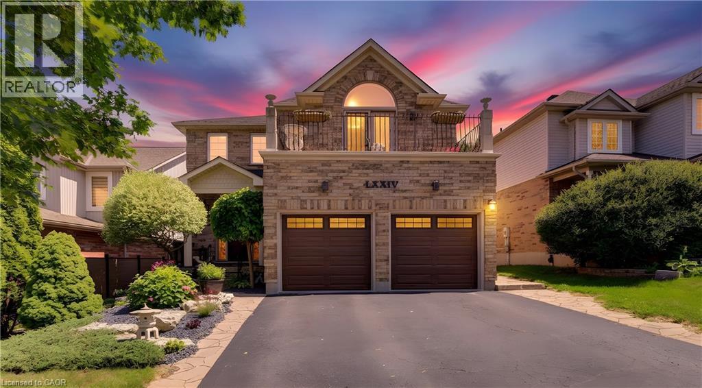 Stone facade residence featuring a two-car garage with panel doors and transom windows - 74 Forest Edge Trail, Kitchener, ON