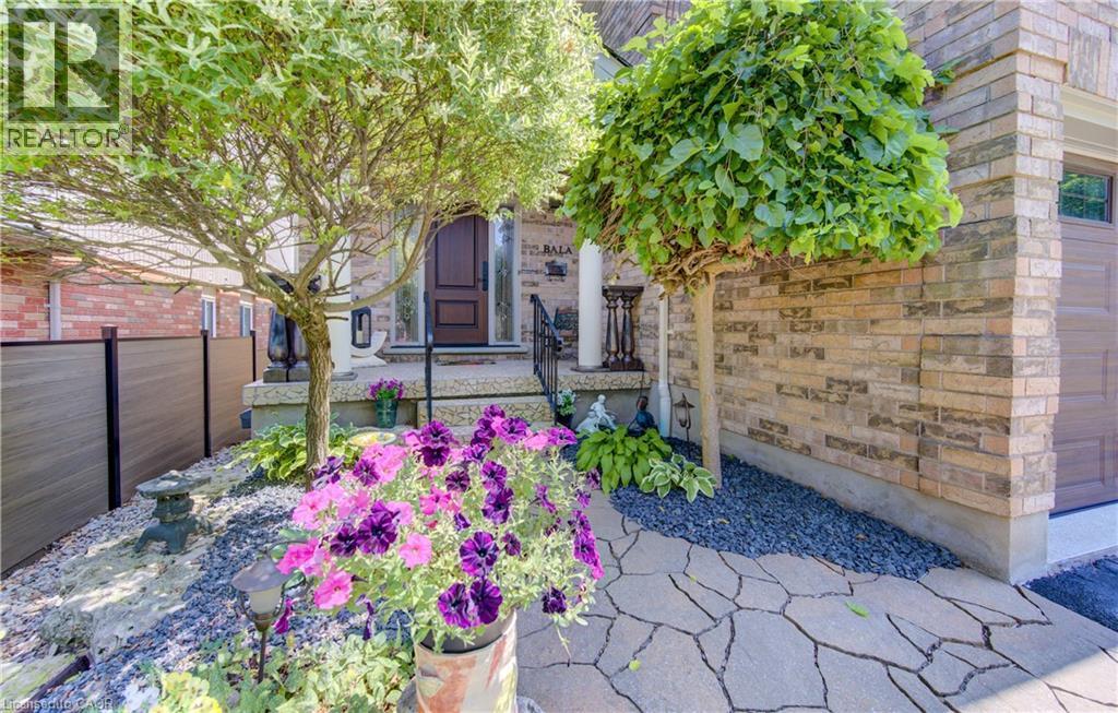 Front entrance featuring a paneled wood door, stone porch, wrought iron railings, and a flagstone walkway - 74 Forest Edge Trail, Kitchener, ON