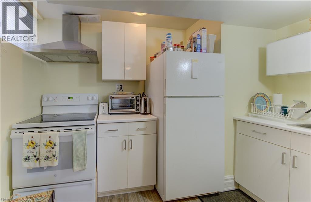 Kitchen area featuring white cabinetry, a stainless steel range hood, a white electric range, and a white refrigerator - 74 Forest Edge Trail, Kitchener, ON