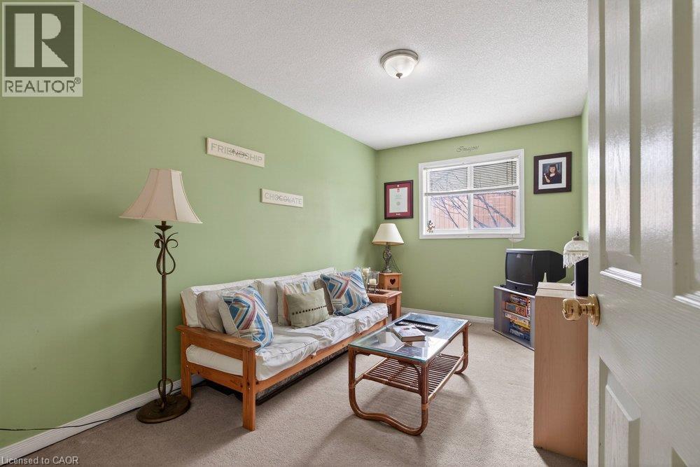 Carpeted room with a ceiling-mounted light fixture, a window with white trim, and a white paneled door with a brass knob - 10 Cadham Boulevard Unit# 29, Hamilton, ON - Indoor