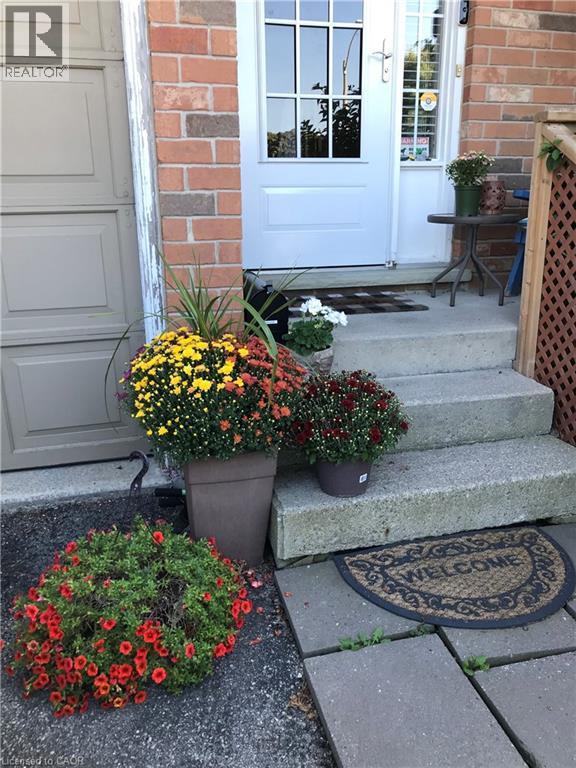 Brick exterior with a paneled garage door and a white entrance door featuring clear glass inserts - 10 Cadham Boulevard Unit# 29, Hamilton, ON - Outdoor With Exterior