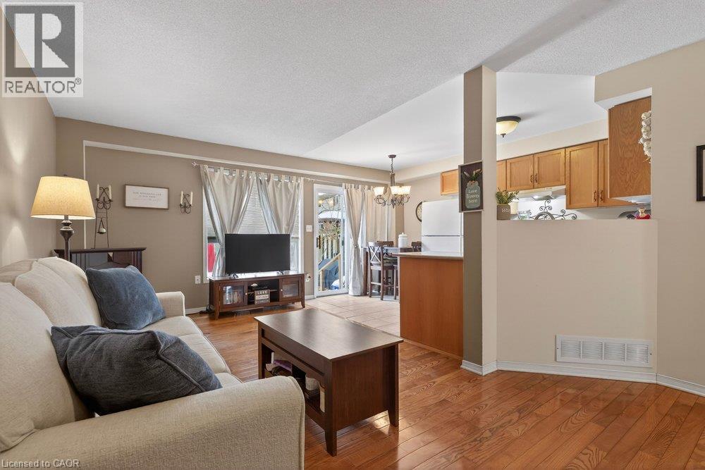 Hardwood flooring, kitchen pass-through, rear patio access, recessed lighting, and ceiling light fixture - 10 Cadham Boulevard Unit# 29, Hamilton, ON - Indoor Photo Showing Living Room