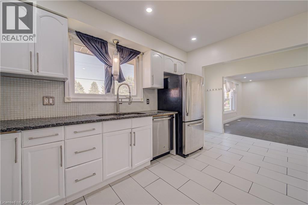 White cabinetry with stainless steel hardware, dark stone countertops, tile backsplash, stainless steel appliances, and tile flooring - 161 Kipling Avenue, Kitchener, ON - Indoor Photo Showing Kitchen