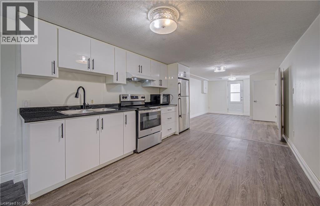 Kitchen featuring white cabinetry, dark stone-finish countertops, stainless steel appliances, and wood-finish flooring - 161 Kipling Avenue, Kitchener, ON - Indoor Photo Showing Kitchen