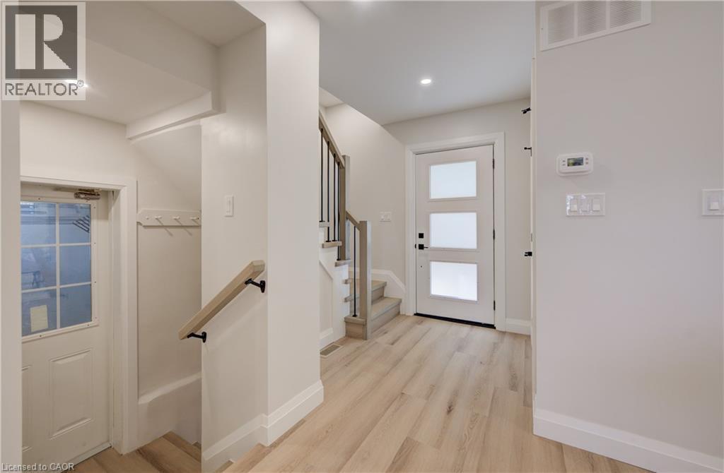 Light wood-finish flooring, staircase with wood handrail and black metal spindles, recessed ceiling lighting, and white interior doors - 34 Moore Avenue N, Waterloo, ON - Indoor Photo Showing Other Room