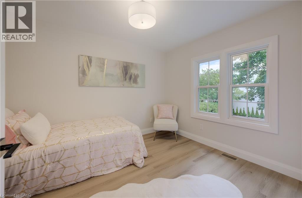 Light-toned wood-finish flooring, white walls, and a contemporary ceiling light fixture - 34 Moore Avenue N, Waterloo, ON - Indoor Photo Showing Bedroom