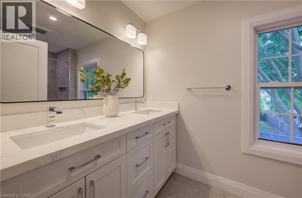 Dual undermount sinks with chrome fixtures, white vanity cabinetry with brushed nickel hardware, and a large wall-mounted mirror - 34 Moore Avenue N, Waterloo, ON - Indoor Photo Showing Bathroom