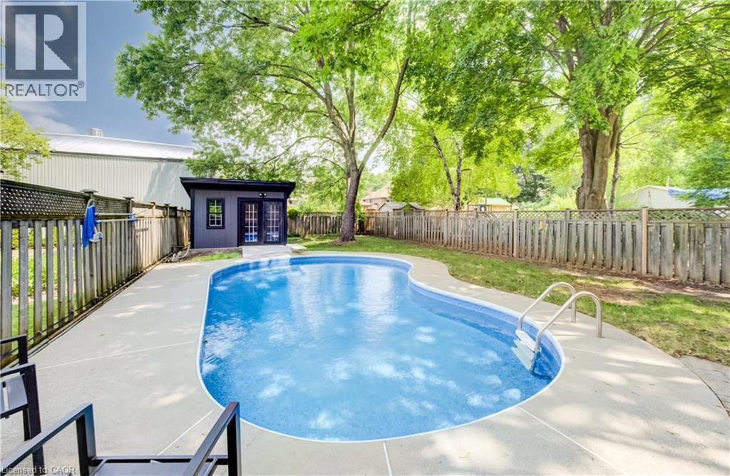 Curved inground swimming pool with light blue liner and integrated steps - 34 Moore Avenue N, Waterloo, ON - Outdoor With In Ground Pool With Backyard