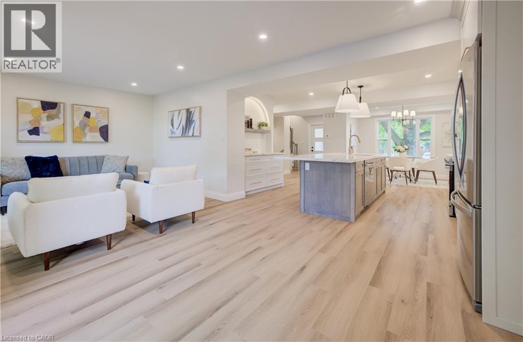 Light wood-finish flooring throughout, recessed lighting, kitchen island with built-in sink, stainless steel refrigerator, and pendant lighting - 34 Moore Avenue N, Waterloo, ON - Indoor