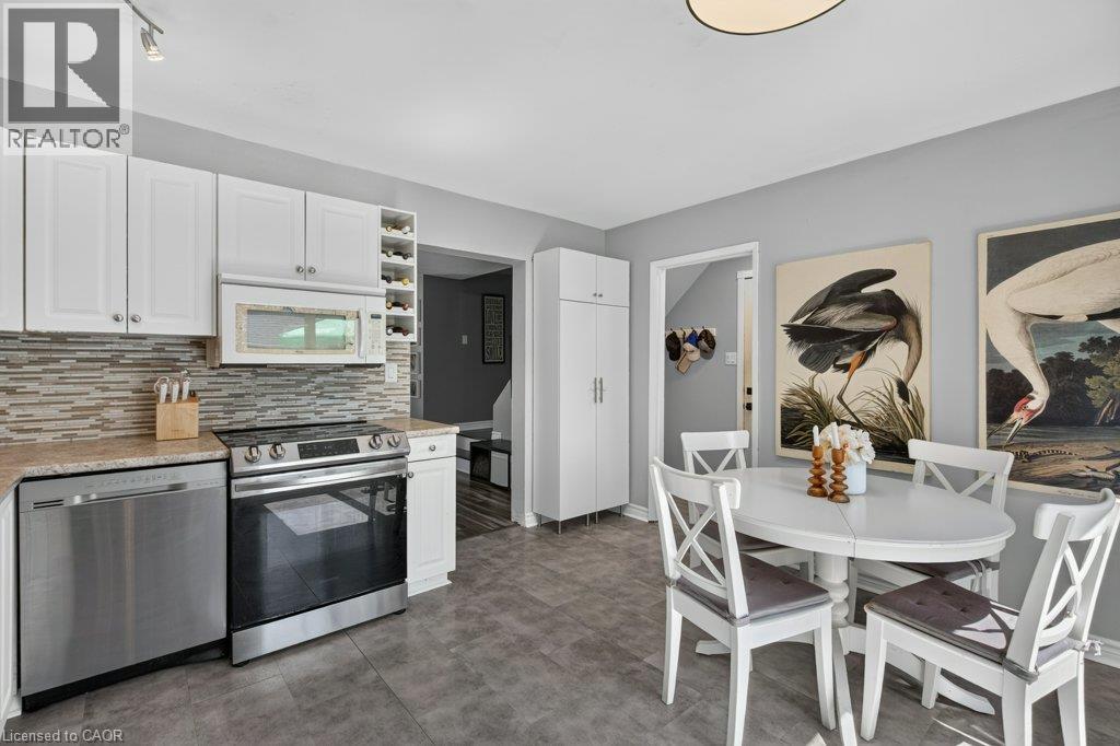 White cabinetry, stainless steel appliances, mosaic tile backsplash, solid surface countertops, and ceramic tile flooring - 60 Elford Crescent, Hamilton, ON - Indoor