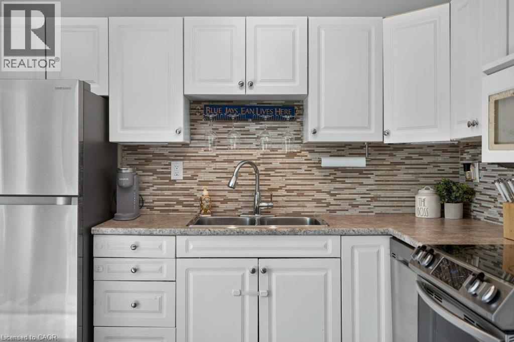 Modern kitchen featuring white shaker cabinetry, granite countertops, and a linear tile backsplash in warm earth tones - 60 Elford Crescent, Hamilton, ON - Indoor Photo Showing Kitchen With Double Sink With Upgraded Kitchen