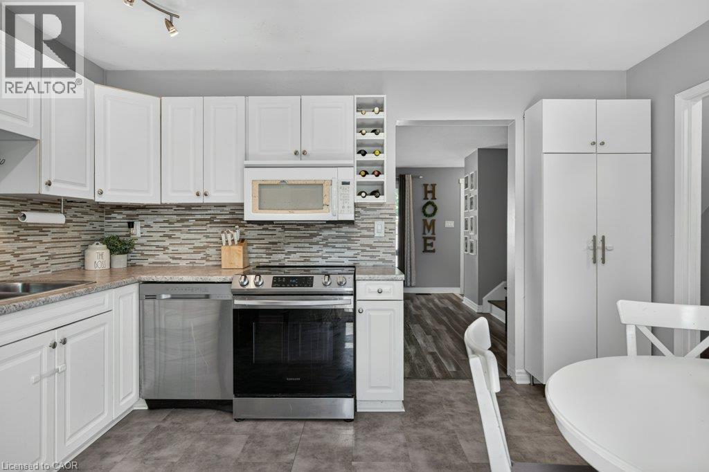 White cabinetry, stainless steel appliances, stone-finish countertops, mosaic tile backsplash, and a built-in wine rack - 60 Elford Crescent, Hamilton, ON - Indoor Photo Showing Kitchen With Upgraded Kitchen