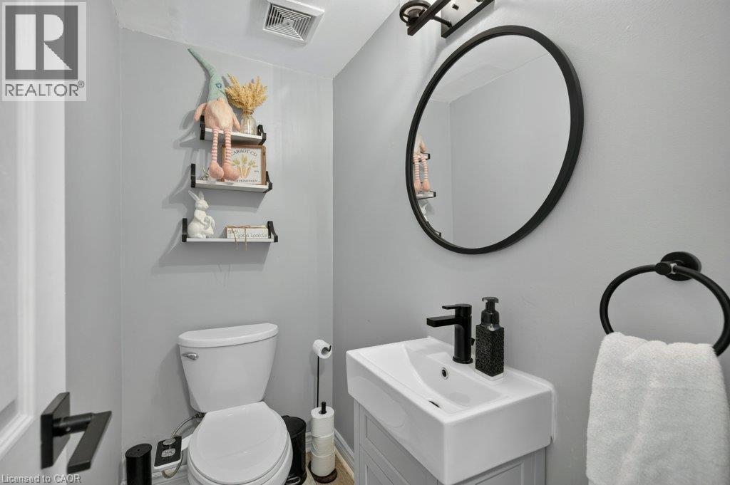 Wall-mounted vanity with a rectangular basin sink and matte black faucet, complemented by a round framed mirror - 60 Elford Crescent, Hamilton, ON - Indoor Photo Showing Bathroom