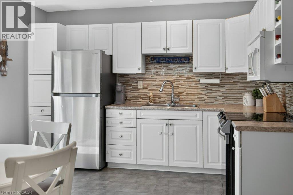Stainless steel refrigerator, white shaker-style cabinetry, mosaic tile backsplash, countertop with integrated sink, and ceramic cooktop - 60 Elford Crescent, Hamilton, ON - Indoor Photo Showing Kitchen With Double Sink With Upgraded Kitchen