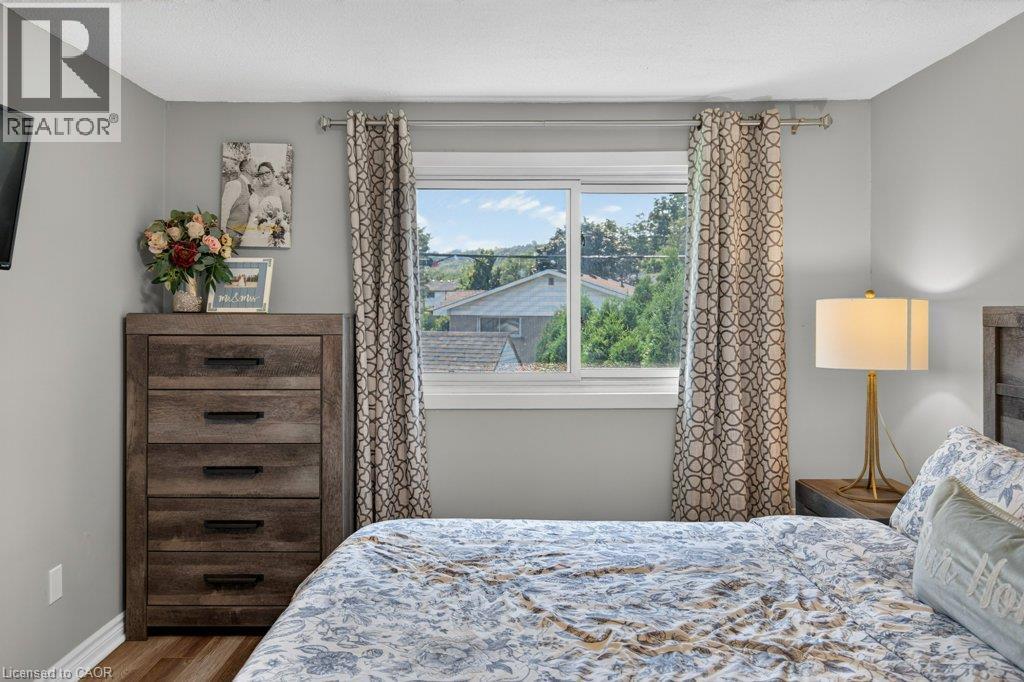 Sliding window with white trim, light gray painted walls, and wood-finish flooring - 60 Elford Crescent, Hamilton, ON - Indoor Photo Showing Bedroom