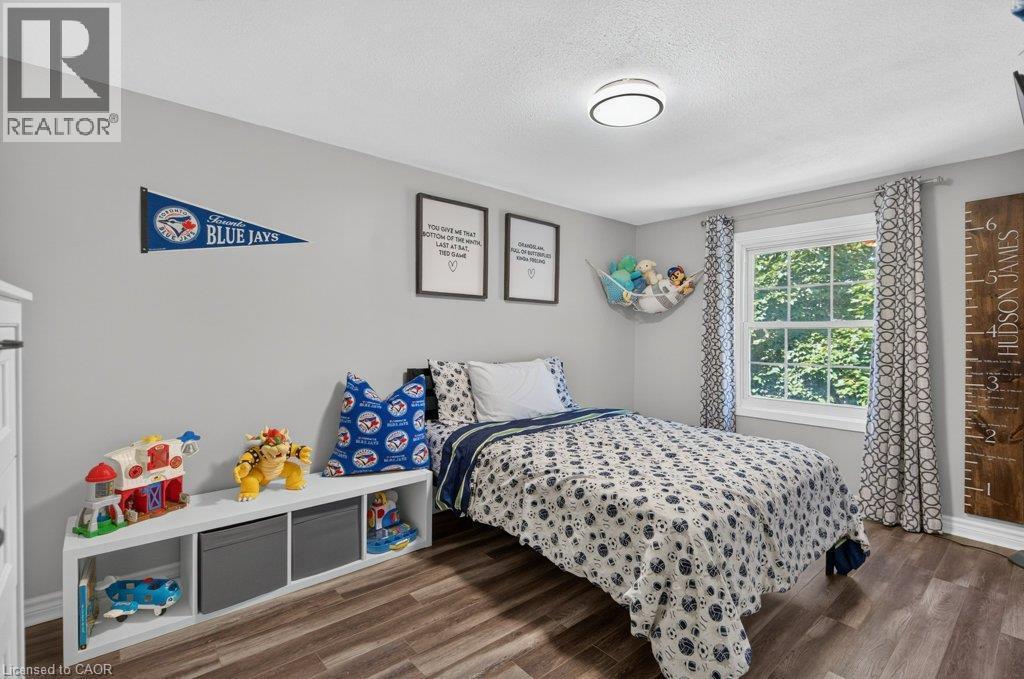 Bright bedroom retreat featuring wood-finish flooring, large windows with natural light, and built-in storage cabinetry with open shelving - 60 Elford Crescent, Hamilton, ON - Indoor Photo Showing Bedroom