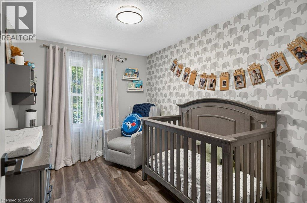 Wood-finish flooring, recessed ceiling lighting, a window with natural light, and a patterned accent wall - 60 Elford Crescent, Hamilton, ON - Indoor Photo Showing Bedroom