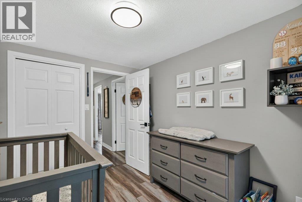 Nursery featuring soft gray walls, wood-finish flooring, and a gray dresser with multiple drawers and open shelving - 60 Elford Crescent, Hamilton, ON - Indoor Photo Showing Other Room