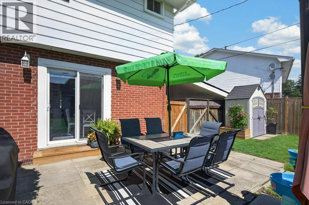 Brick exterior with white siding, concrete patio, sliding glass door, and a detached storage shed - 60 Elford Crescent, Hamilton, ON - Outdoor With Deck Patio Veranda With Exterior