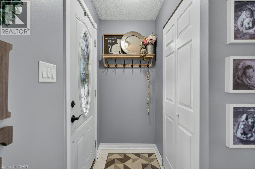 White paneled entry door with an oval decorative glass insert and black hardware - 60 Elford Crescent, Hamilton, ON - Indoor Photo Showing Other Room
