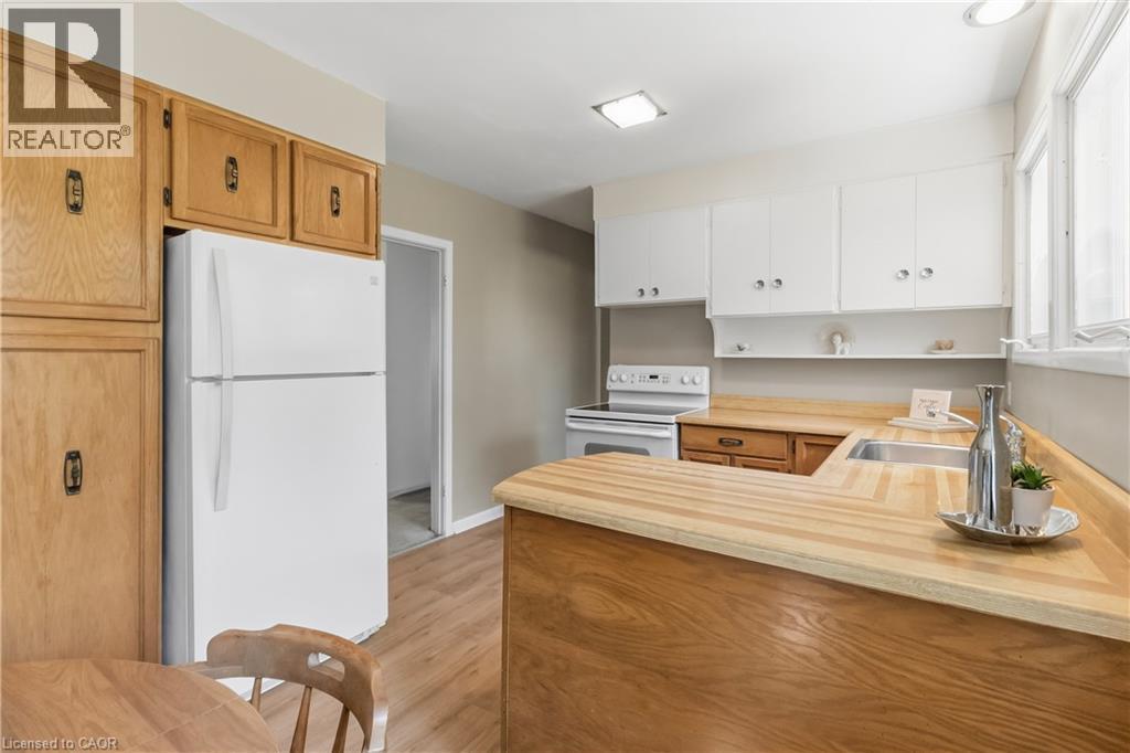 Kitchen featuring wood-finish countertops, white cabinetry, a built-in stainless steel sink, and wood-finish flooring - 974 Unsworth Avenue, Burlington, ON