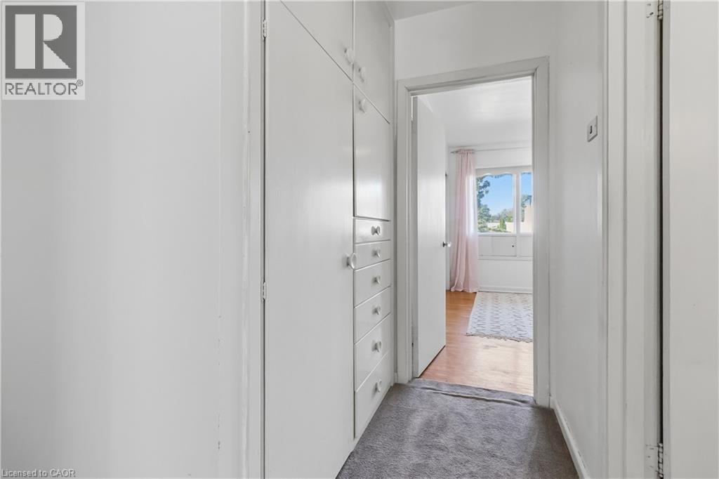 Bright hallway with white painted walls, built-in cabinetry with multiple drawers for ample storage, and wood-finish flooring - 974 Unsworth Avenue, Burlington, ON