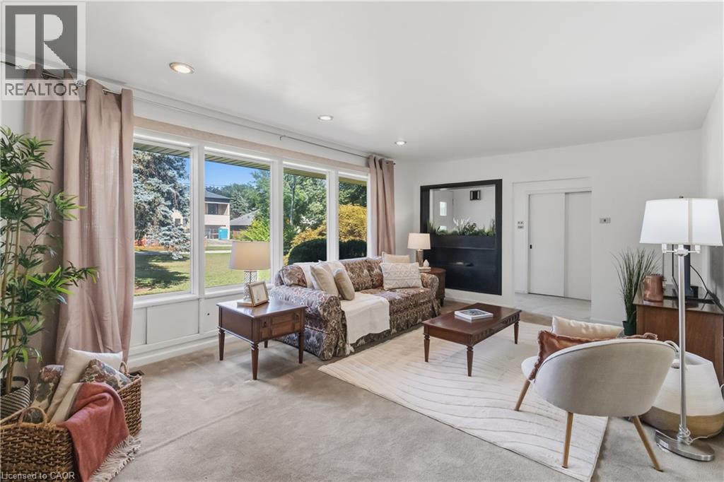 Bright and airy living room bathed in natural light from expansive multi-pane glass doors and windows overlooking manicured grounds - 974 Unsworth Avenue, Burlington, ON