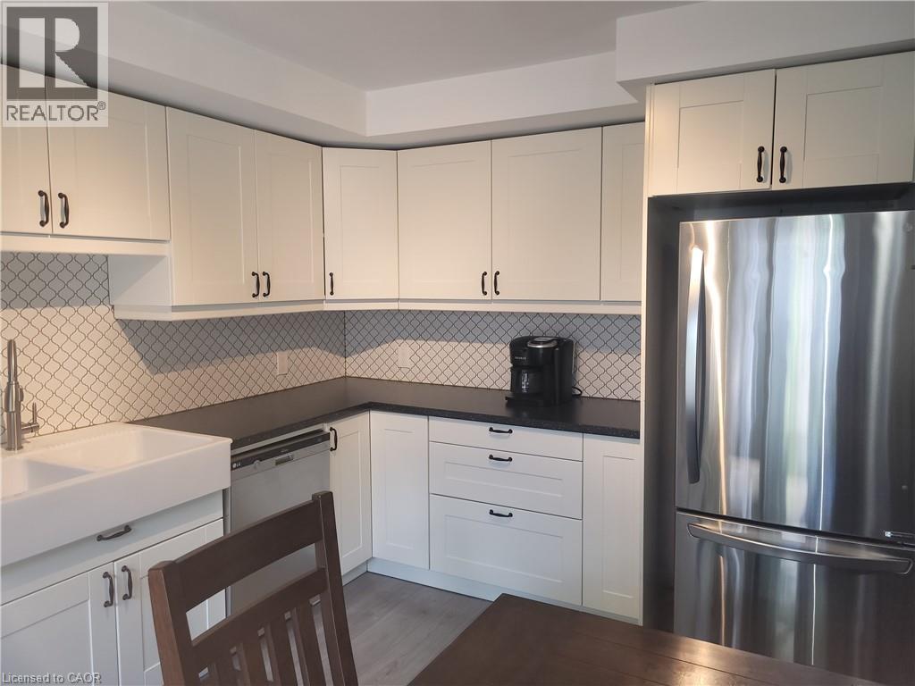 Modern kitchen featuring crisp white cabinetry with brushed nickel hardware, a geometric tile backsplash, and stainless steel appliances including a refrigerator with French doors - 23 Bentley Place, Hamilton, ON - Indoor Photo Showing Kitchen