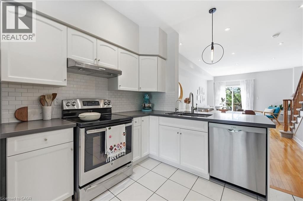 Modern kitchen featuring white cabinetry, subway tile backsplash, stainless steel appliances, and dark countertops - 678 Rowley Common, Burlington, ON - Indoor Photo Showing Kitchen With Stainless Steel Kitchen With Upgraded Kitchen