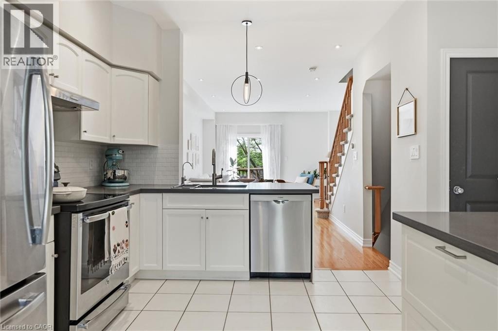 Contemporary kitchen featuring white cabinetry, dark countertops, a white subway tile backsplash, stainless steel appliances, and a pendant light fixture - 678 Rowley Common, Burlington, ON - Indoor Photo Showing Kitchen With Stainless Steel Kitchen With Upgraded Kitchen
