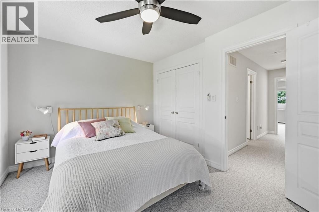Bedroom featuring light grey walls, textured carpeting, a ceiling fan with integrated lighting, and white bi-fold closet doors - 678 Rowley Common, Burlington, ON - Indoor Photo Showing Bedroom
